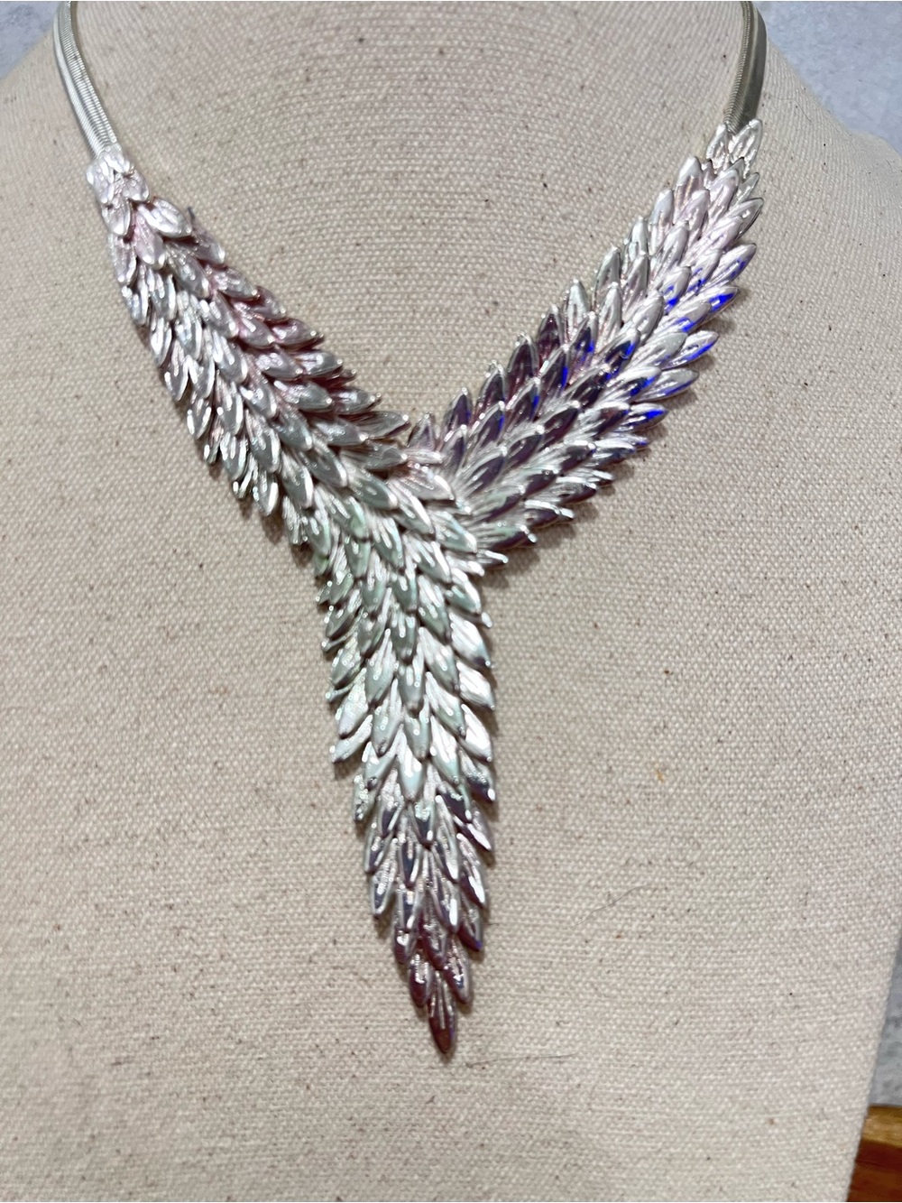 Chunky silver-toned statement necklace featuring articulated metal feathers